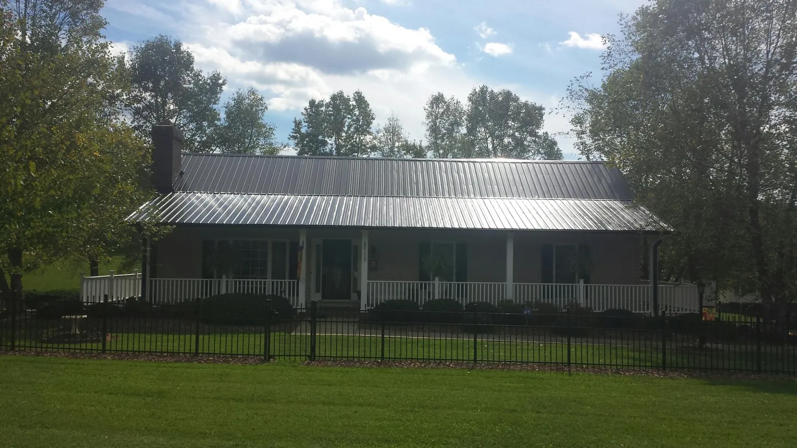 Gray metal roof on a brick ranch with a full width front porch — Gutter Guard Installation work by our crew in Kimball